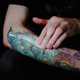 Daily Tattoo Lotion (12.0 oz) Saniderm Tattoo Aftercare in use on a tattooed arm